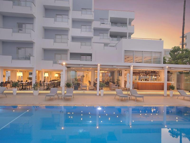 Moderner Hotelpool bei Sonnenuntergang mit Beleuchtung und Liegestühlen.