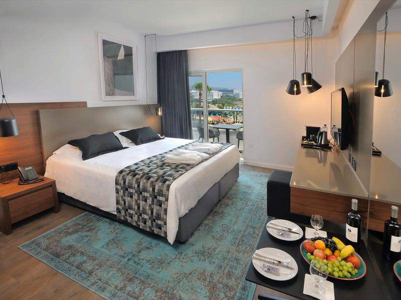 Modernes Hotelzimmer mit Doppelbett, Balkon und Blick auf Stadt und Wasser