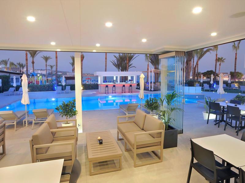 Moderner Innenbereich mit Sitzmöbeln und Blick auf beleuchteten Außenpool bei Abenddämmerung.