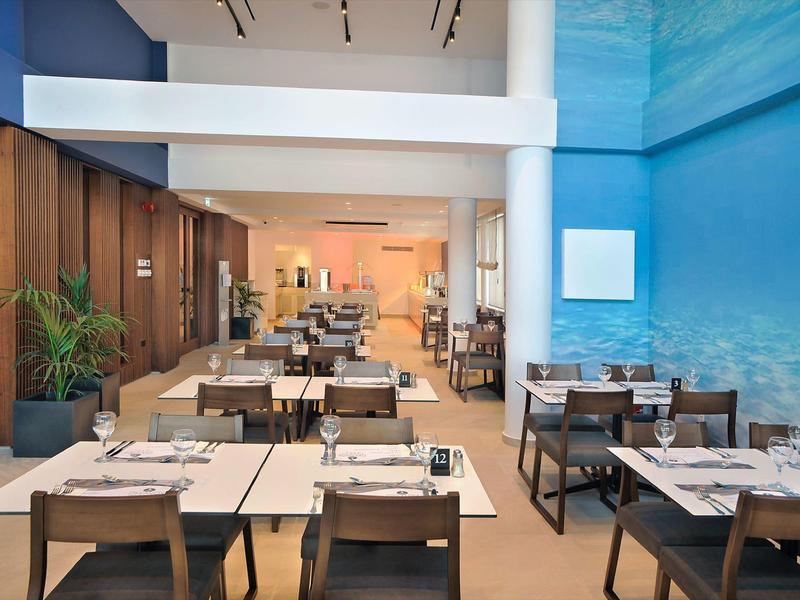 Modernes Restaurant mit Holzmöbeln und einer blau gestalteten Wand, ideal für Hotelgäste.