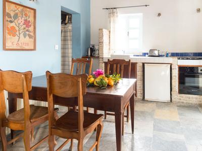 Útulná kuchyně s dřevěným stolem, židlemi a čerstvým ovocem na stole.