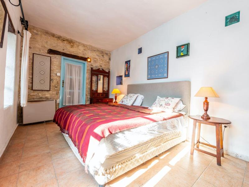 Helles Schlafzimmer mit großem Bett, roter Decke und dekorativen Bildern an weißen Wänden.