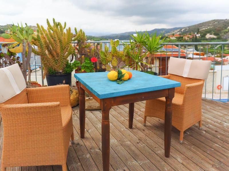 Terrasse mit Tisch und Stühlen, Obst auf dem Tisch und Blick auf Hügel im Hintergrund