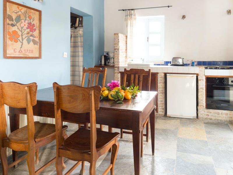 Ein rustikaler Essbereich mit Holztisch, Stühlen und Blumen in einer hellen Küche.