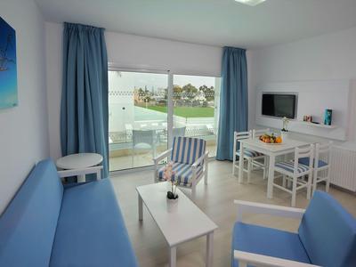Helles Wohnzimmer mit blauen Möbeln und Blick auf Terrasse und Swimmingpool.