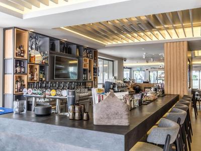 Moderner Hotelbarbereich mit langer Bartheke, Holzakzenten und bequemen Sitzgelegenheiten.