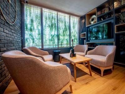 Gemütliche Hotel-Lounge mit bequemen Sesseln, Holzboden und großem Fenster mit grüner Aussicht.