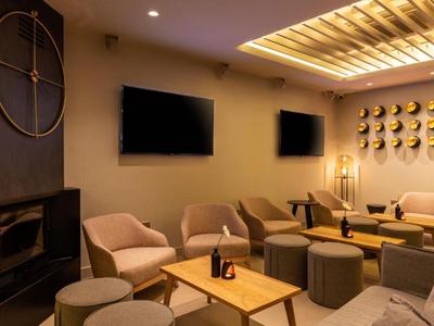 Gemütlicher Hotel-Loungebereich mit bequemen Sesseln, Tischen und warmen Deckenleuchten.