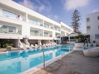 Moderner Hotelpool mit weißen Liegestühlen und klar blauem Wasser unter blauem Himmel.