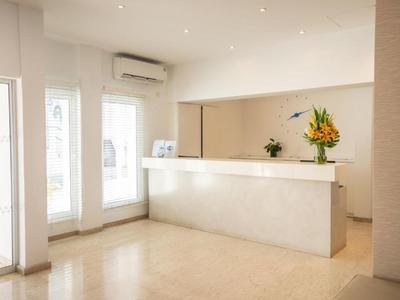 Moderner weißer Hotellobby-Empfang mit Blumenarrangement und heller Beleuchtung