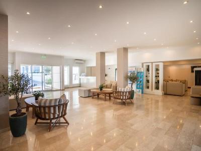 Großer Hotel-Loungebereich mit hellen Marmorböden, modernen Sitzmöbeln und großen Fenstern.