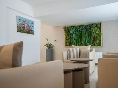 Modern eingerichteter Hotel-Loungebereich mit grüner Pflanzenwand und gemütlichen Sesseln.