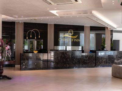 Moderner Hotel-Empfang mit dunkler Marmor-Rezeption und Blumendekoration.