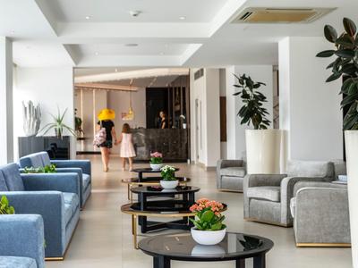 Helles, modernes Hotellobby mit Sofas, Sesseln und kleinen Tischen mit Pflanzen.