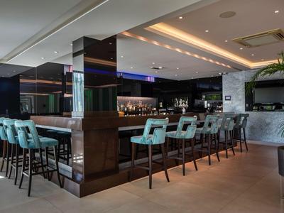 Moderner Hotelbarbereich mit hohen, gepolsterten Stühlen und stilvoller Beleuchtung.
