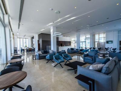 Moderner Hotel-Lounge-Bereich mit blauen Sesseln und großen Fenstern.