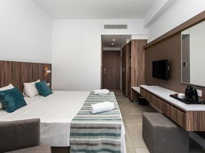 Modernes Hotelzimmer mit zwei Betten, Holzdetails und Fernseher an der Wand.