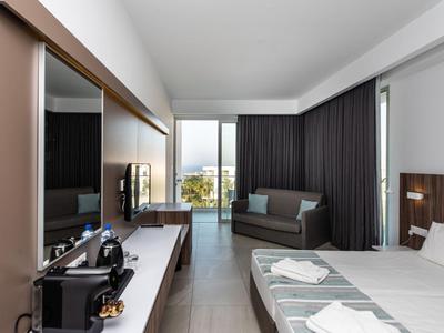 Modern eingerichtetes Hotelzimmer mit Doppelbett, Fernseher und Balkon mit Ausblick.