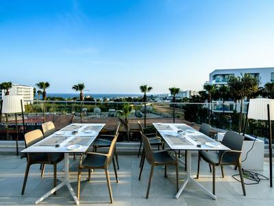 Modernes, offenes Hotelrestaurant mit Meerblick und stilvollen Tischen im Freien.