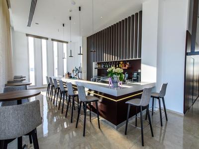 Moderner Hotelbarbereich mit Hockern und langer Sitzbank in einem hellen Raum.