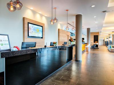 Reception d'hotel moderna con banco, monitor e lampade decorative.