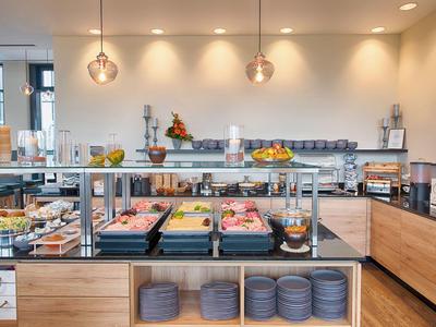 Espace petit-déjeuner d'hôtel moderne avec pâtisseries variées, fruits et éclairage moderne