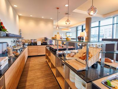 Buffet luminoso con pasticceria, pane e caffè in una sala colazione moderna.