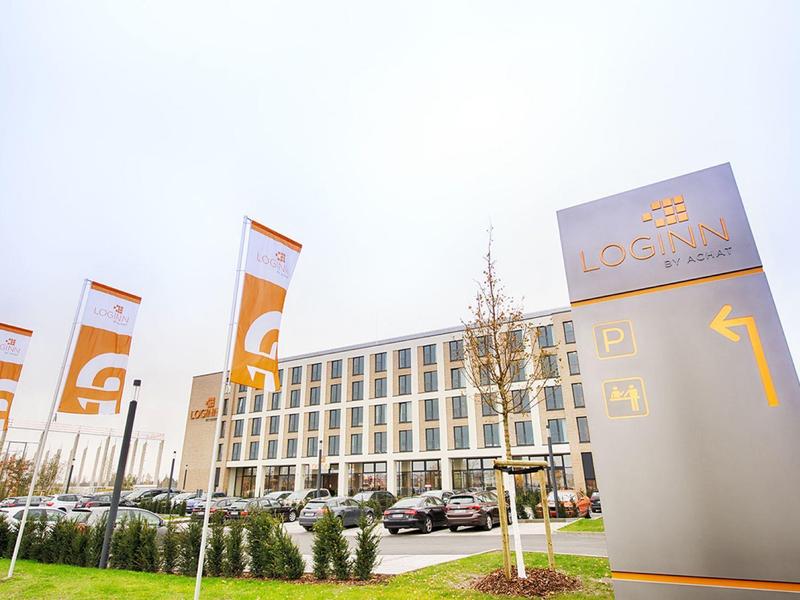 Bâtiment d'hôtel moderne avec drapeaux et grand panneau par une journée claire.