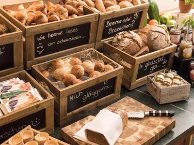 Various fresh breads and pastries displayed on a rustic buffet with wooden signs.