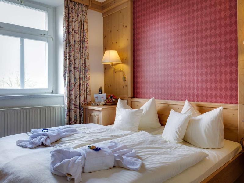 Gezellige hotelkamer met tweepersoonsbed, badjassen en warm houten meubilair.