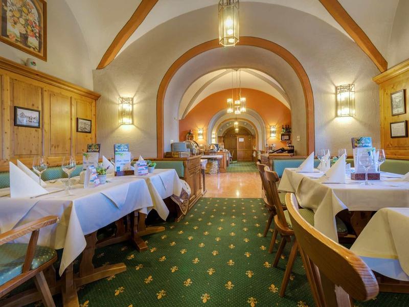 Gezellige hotel eetzaal met houten meubels, witte tafelkleden en balkenplafonds.