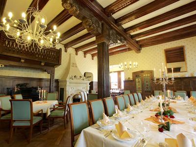 Eleganter Speisesaal mit Holzbalken, Kronleuchtern und festlich gedeckten Tischen.