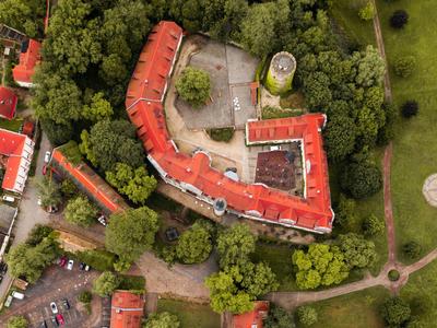 Aerial view of a red building complex surrounded by trees and greenery.
