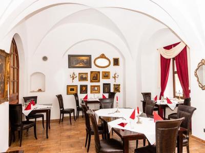 Weißer Gastraum mit gewölbter Decke und rot dekorierten Fenstern in einem Restaurant.