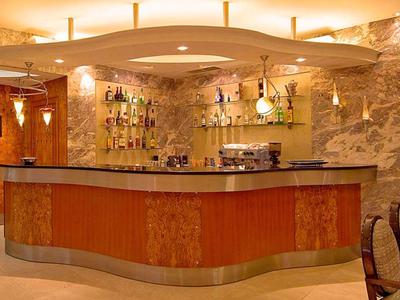 Bar d'hôtel élégante avec éclairage chaleureux, panneaux en bois et diverses bouteilles sur étagères.