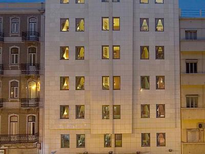 Bâtiment d'hôtel moderne éclairé avec une entrée illuminée et de nombreuses fenêtres au crépuscule.