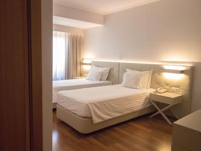 Chambre d'hôtel confortable avec deux lits, sol en bois et éclairage doux.