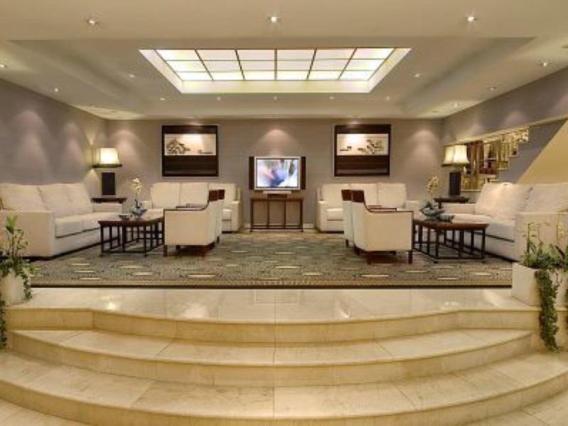 Salon d'hôtel élégant avec fauteuils blancs, tapis et éclairage au plafond.