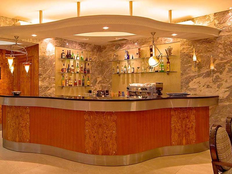 Bar d'hôtel élégante avec éclairage chaleureux, panneaux en bois et diverses bouteilles sur étagères.