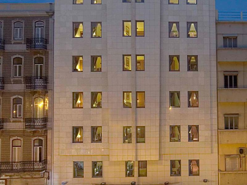 Bâtiment d'hôtel moderne éclairé avec une entrée illuminée et de nombreuses fenêtres au crépuscule.