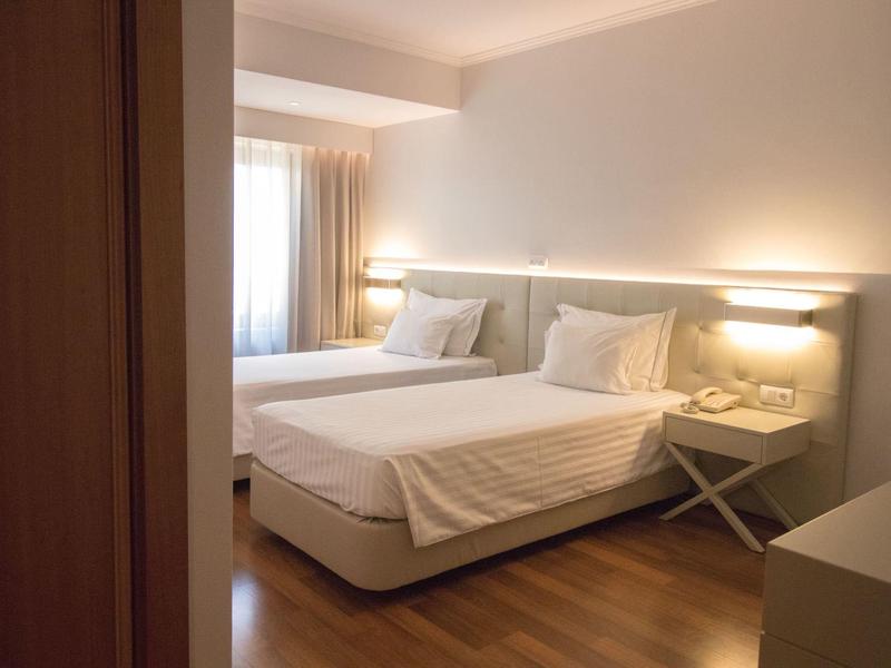 Chambre d'hôtel confortable avec deux lits, sol en bois et éclairage doux.