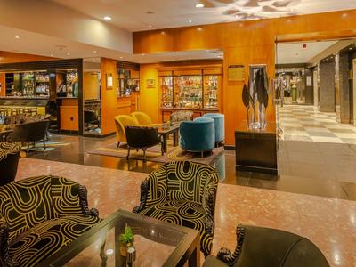 Elegante hotellobby met gezellige fauteuils en een goed gevulde bar.