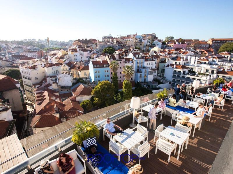 Dakterras met tafels en stoelen met uitzicht op een stad met veel huizen.