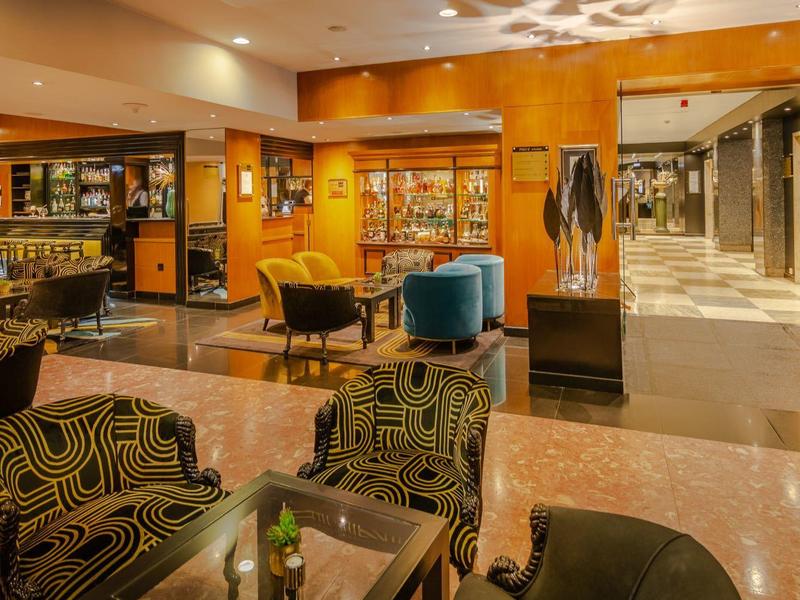 Elegante hotellobby met gezellige fauteuils en een goed gevulde bar.