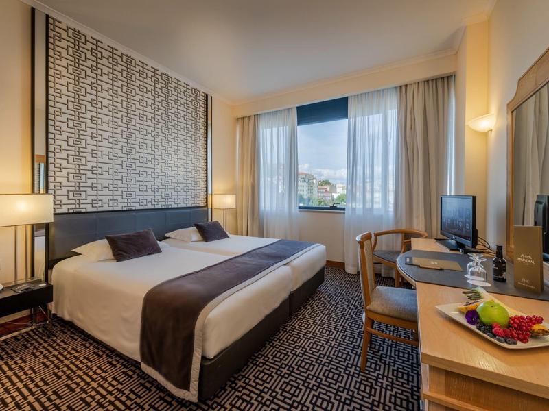 Modern hotelkamer met tweepersoonsbed, bureau, tv en raam met uitzicht naar buiten.