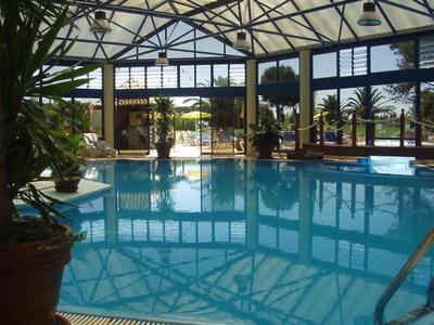 Vnitřní bazén se skleněnými stěnami a tropickými rostlinami v hotelu.