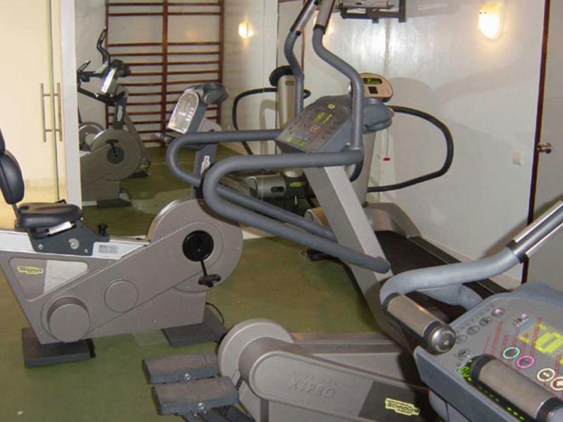 Malá posilovna s různými tréninkovými stroji a mírným osvětlením.