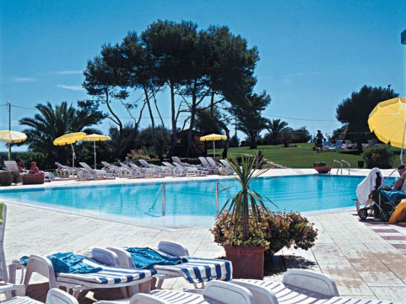 Bazén s lehátky, slunečníky a stromy za slunečného dne