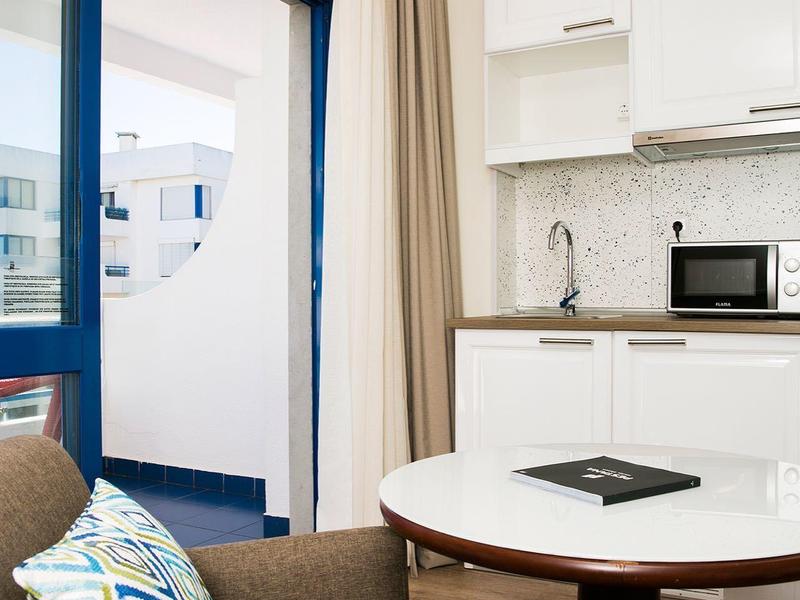 Světý obývací pokoj s hnědými křesly, kulatým stolem a moderní kuchyňskou linkou v pozadí.