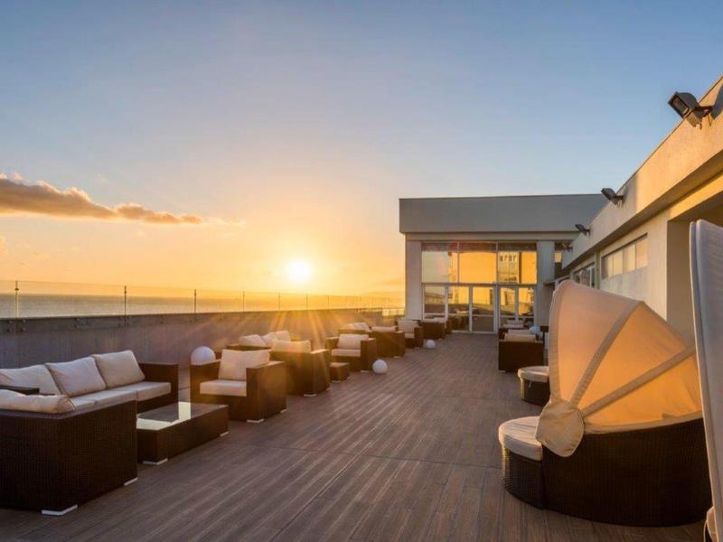 Terraza de hotel con muebles cómodos y vistas al atardecer sobre el mar